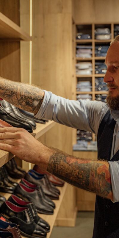Caucasian man browsing leather shoes in a stylish clothing store. Adult male in trendy fashion setting.