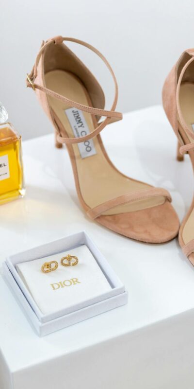 Chic display of luxury sandals, perfume, and jewelry on elegant stands.