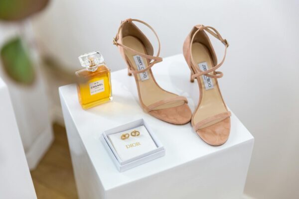 Chic display of luxury sandals, perfume, and jewelry on elegant stands.