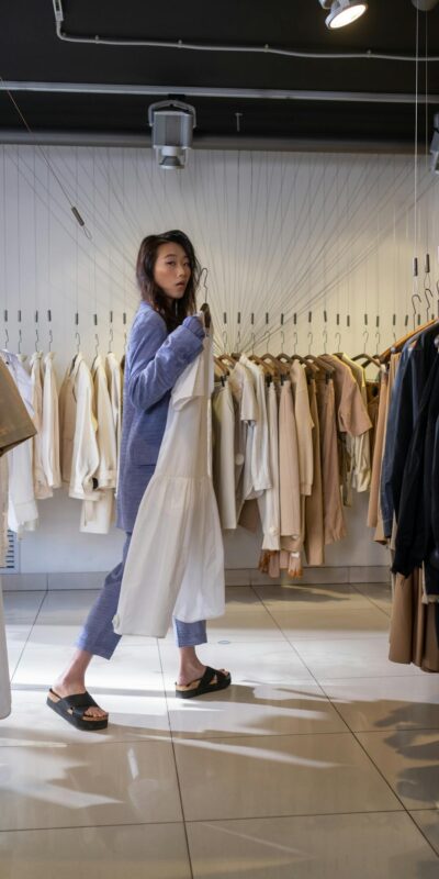 Stylish young woman shopping in a chic clothing boutique, selecting trendy outfits.